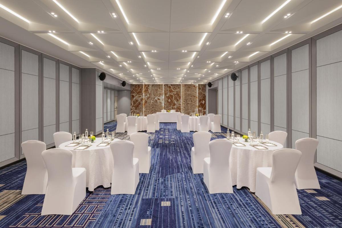 a room with tables and chairs in a room at Le Meridien Ahmedabad in Ahmedabad