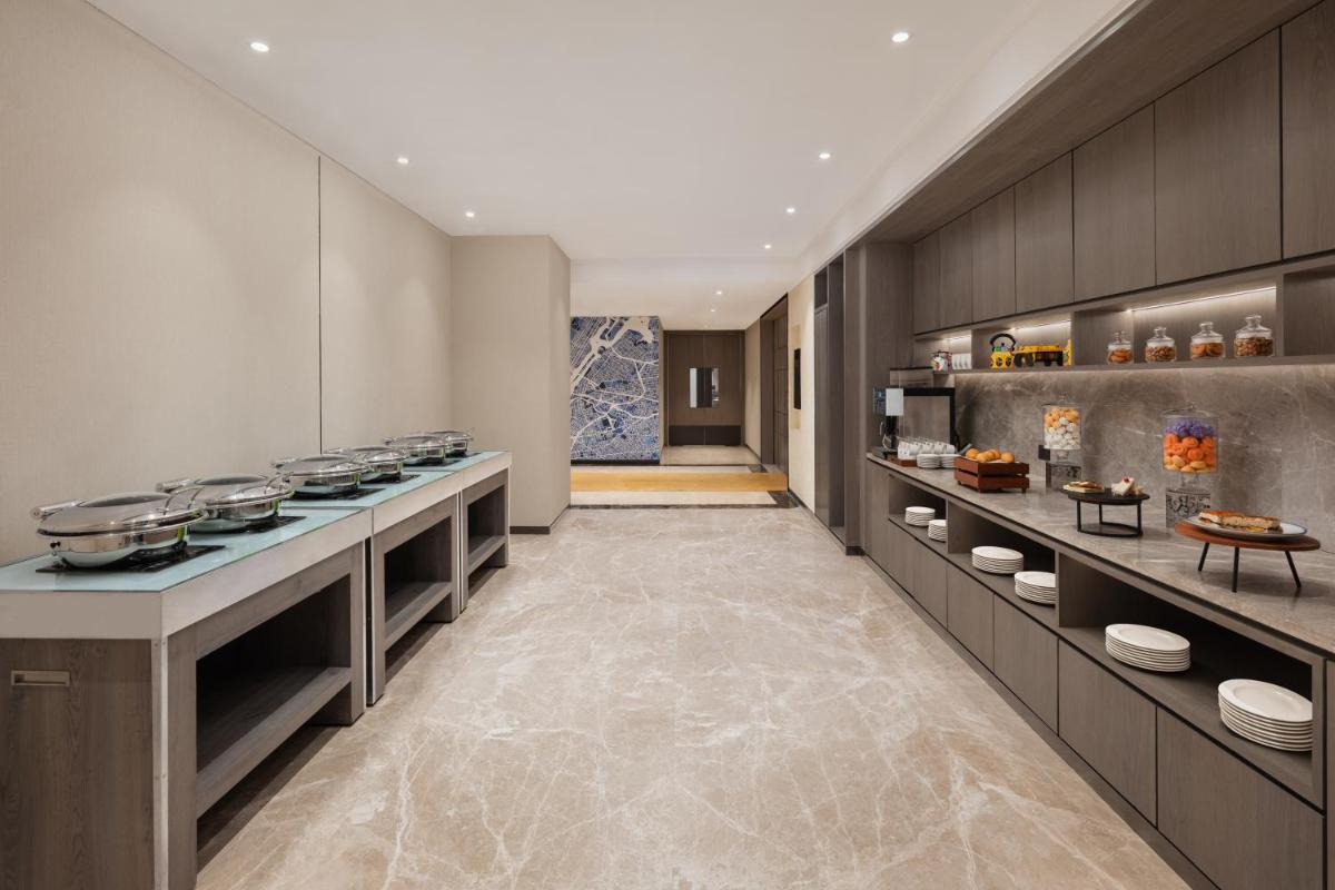 a kitchen with a long counter with food on it at Le Meridien Ahmedabad in Ahmedabad +57 photos