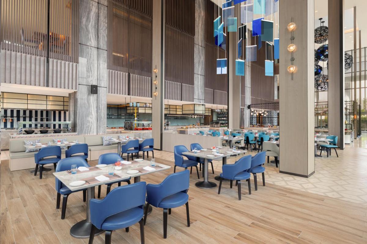 a dining room with tables and blue chairs at Le Meridien Ahmedabad in Ahmedabad