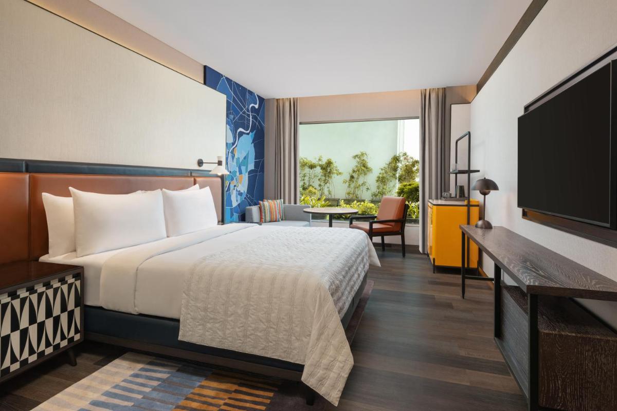 a hotel room with a bed and a flat screen tv at Le Meridien Ahmedabad in Ahmedabad