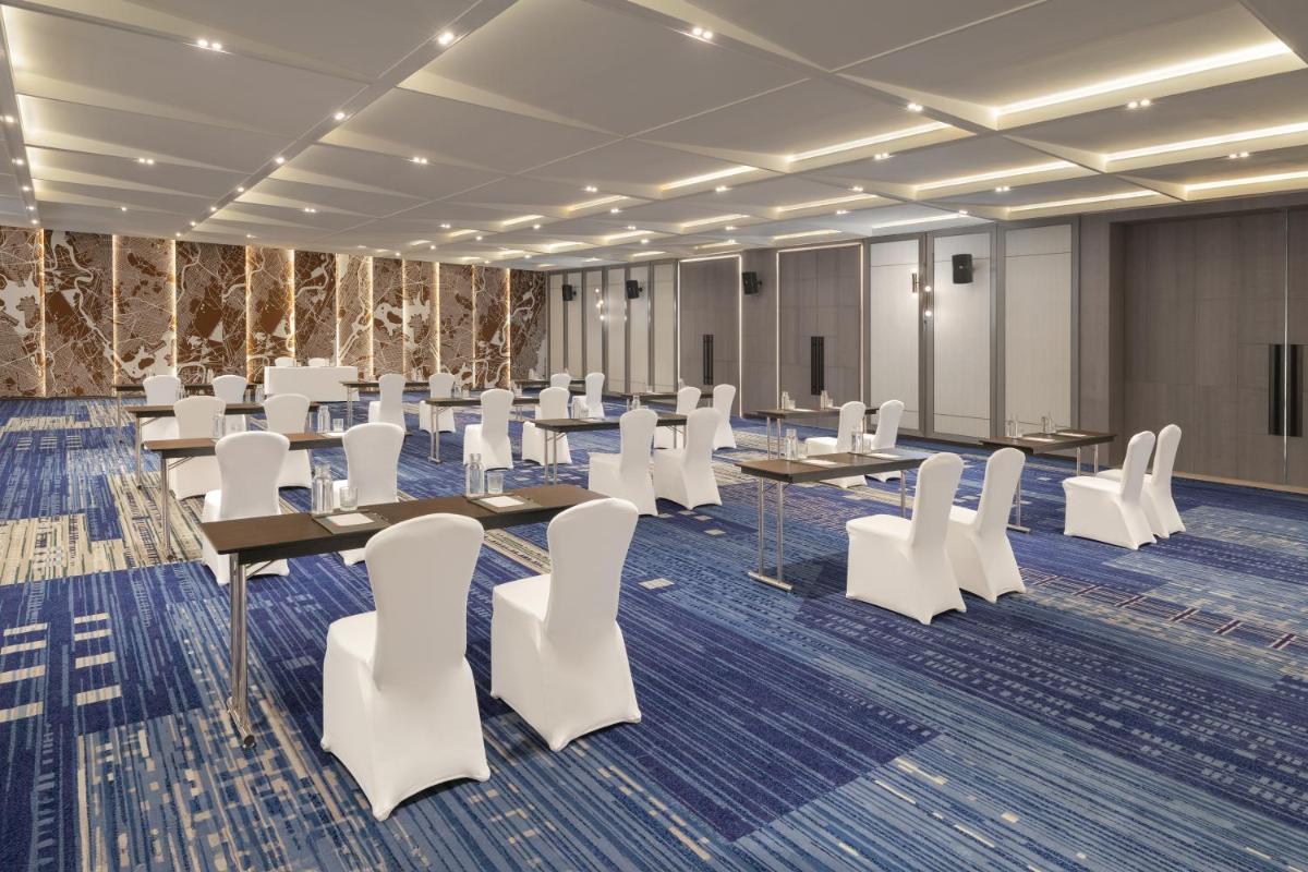 a conference room with tables and white chairs at Le Meridien Ahmedabad in Ahmedabad