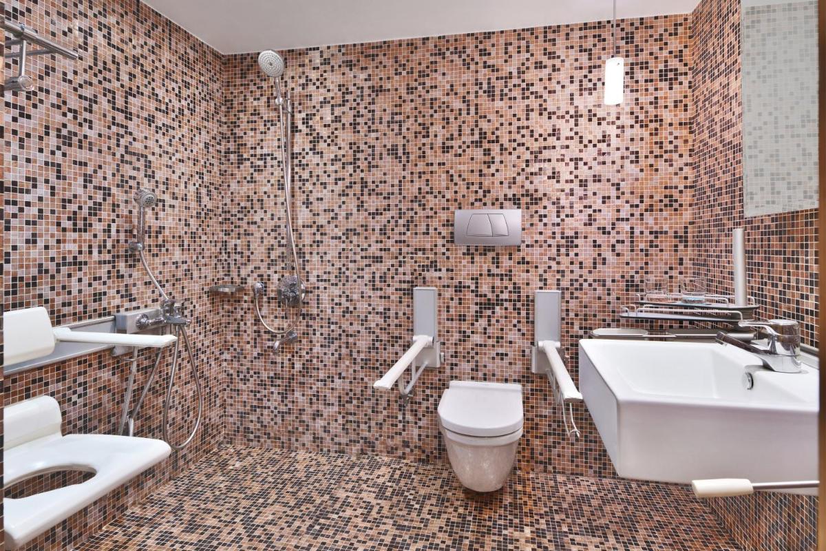 a bathroom with a toilet and a sink and a shower at Le Meridien New Delhi in New Delhi a bathroom with a toilet and a sink and a shower at Le Meridien New Delhi in New Delhi