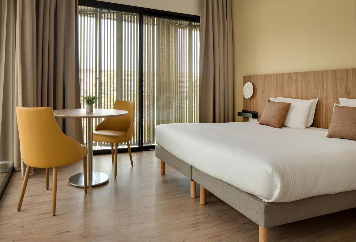 une chambre d'hôtel avec un lit, une table et des chaises dans l'établissement Villa Thermae Nancy, à Nancy