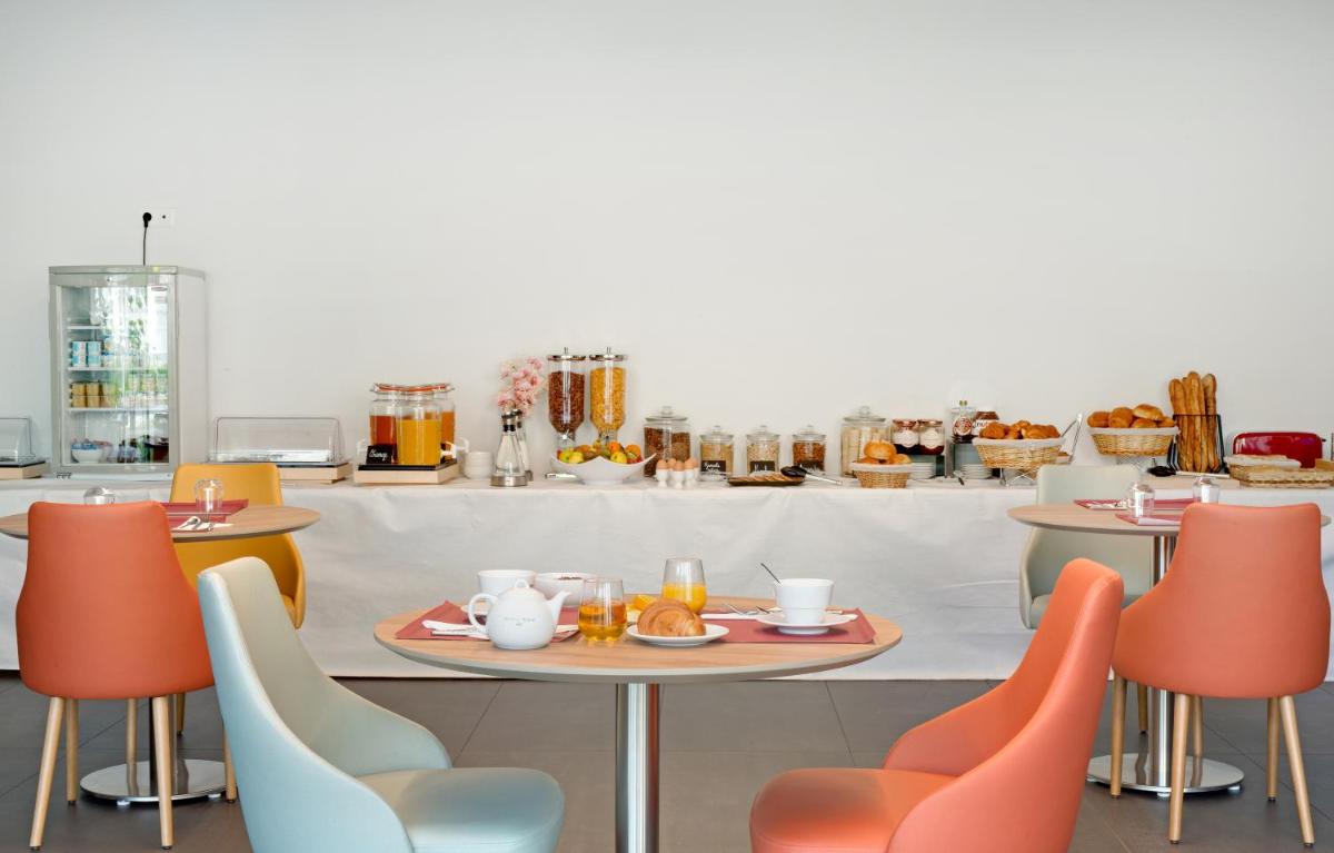 un restaurant avec des chaises orange et une table avec de la nourriture dans l'établissement Villa Thermae Nancy, à Nancy