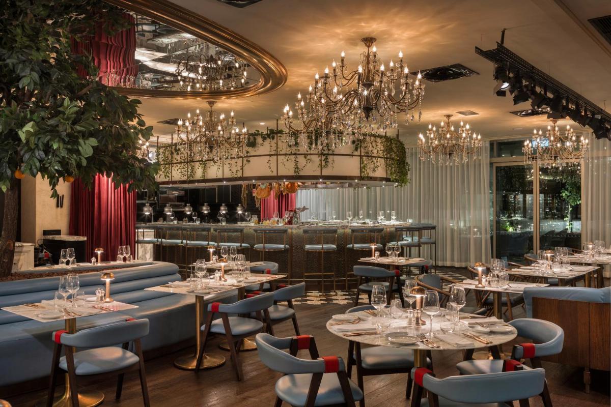 um restaurante com mesas, cadeiras e lustres em EPIC SANA Marquês Hotel em Lisboa