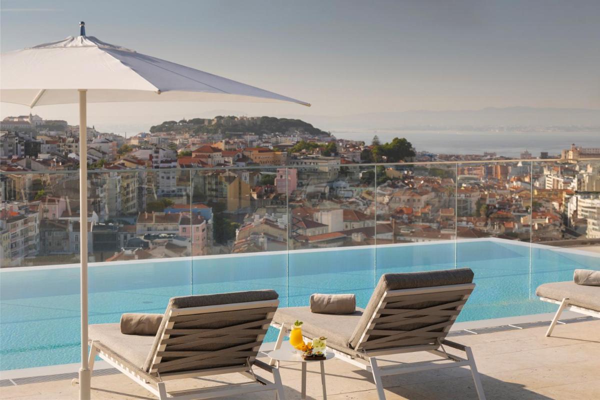 uma piscina com duas cadeiras e um guarda-sol em EPIC SANA Marquês Hotel em Lisboa