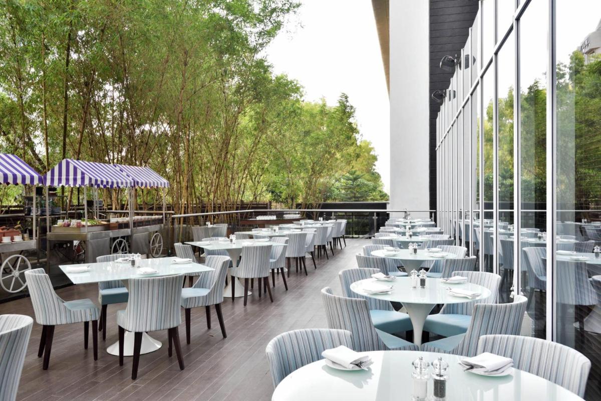 a restaurant with white tables and chairs and windows at Marriott Suites Pune in Pune