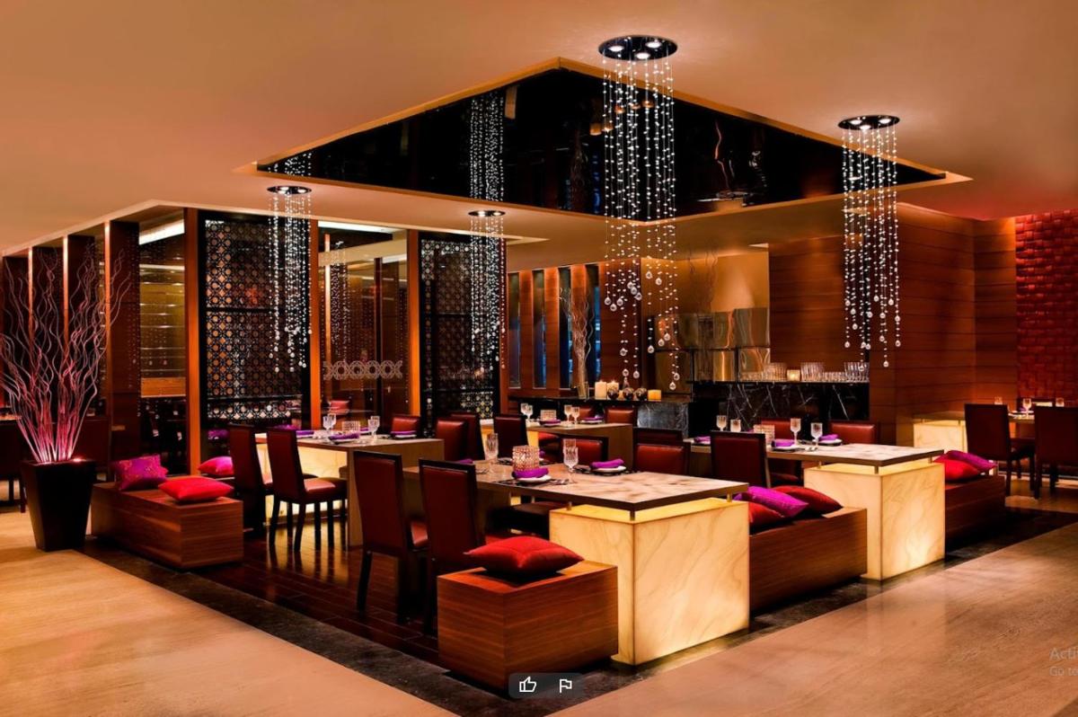 a restaurant with tables and chairs in a room at Le Meridien Ahmedabad in Ahmedabad