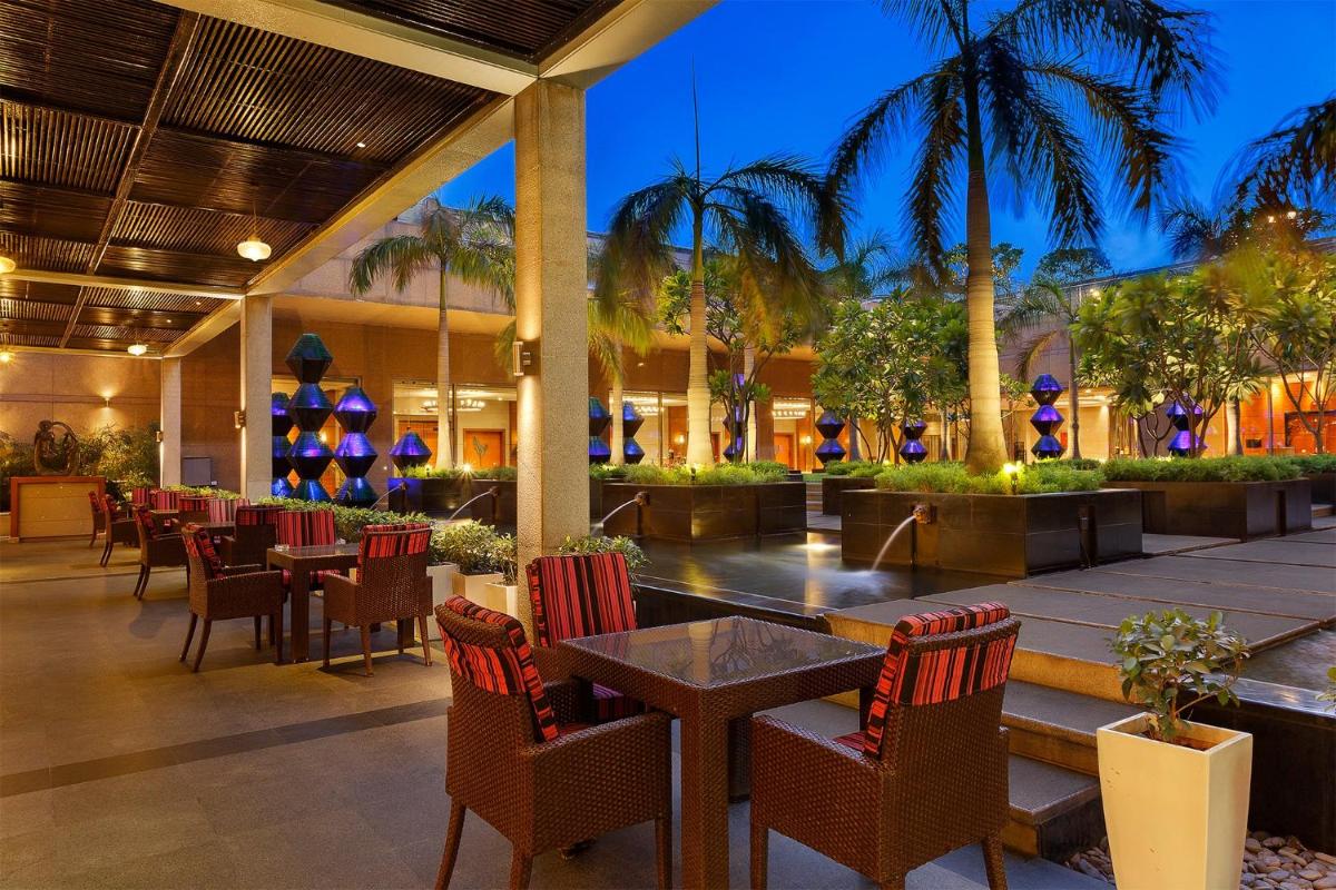 a restaurant with tables and chairs and palm trees at Crowne Plaza Today Gurugram by IHG in Gurgaon a restaurant with tables and chairs and palm trees at Crowne Plaza Today Gurugram by IHG in Gurgaon