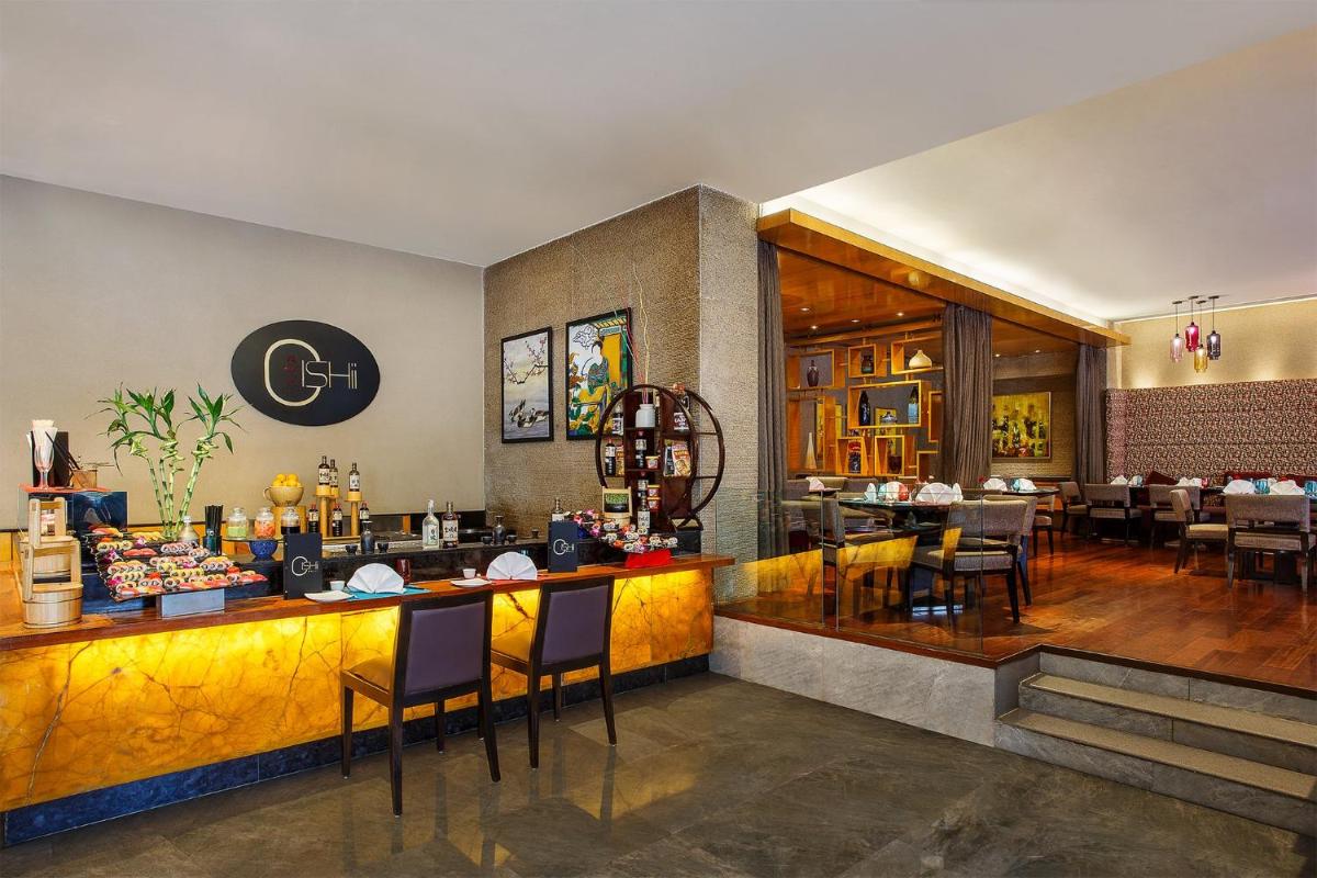 a restaurant with a bar with chairs and tables at Crowne Plaza Today Gurugram by IHG in Gurgaon