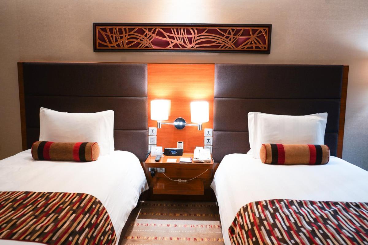 a hotel room with two beds and a desk at Crowne Plaza Today Gurugram by IHG in Gurgaon