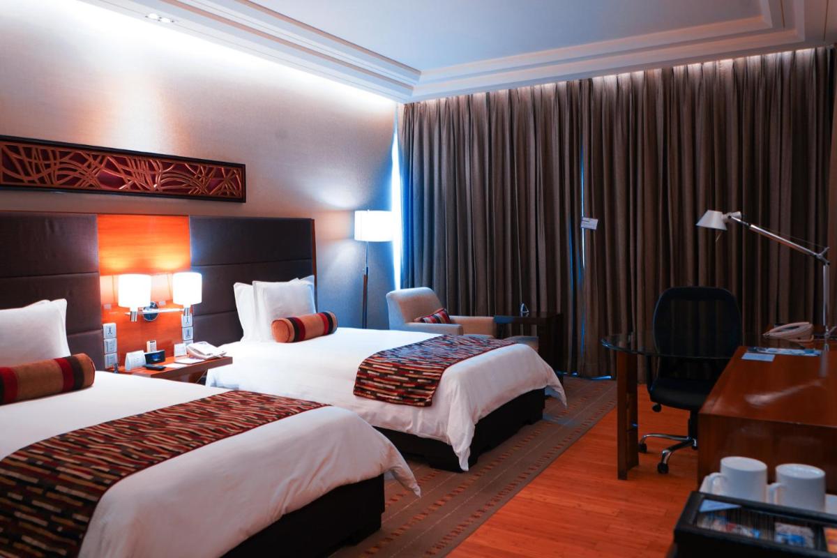 a hotel room with two beds and a desk at Crowne Plaza Today Gurugram by IHG in Gurgaon
