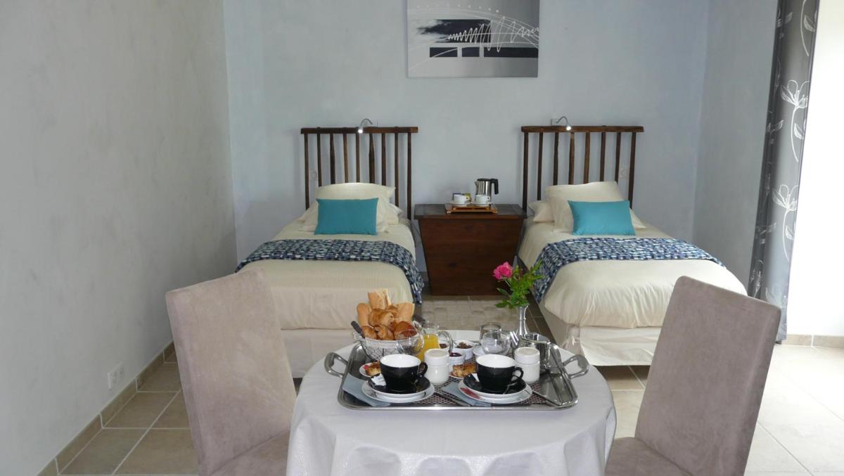 Cette chambre comprend 2 lits et une table avec de la nourriture. dans l'établissement Domaine de Janis & Spa, au Vigan