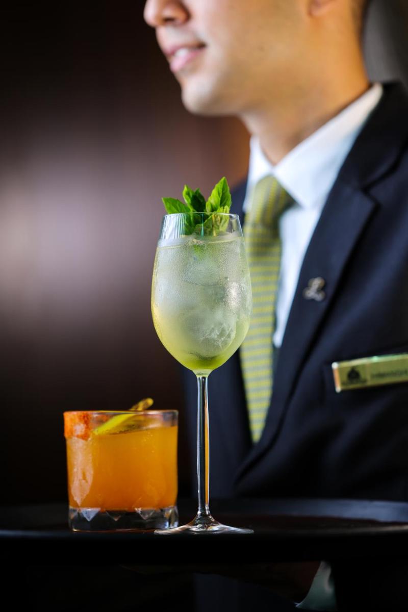 a man in a suit sitting at a table with a drink at The Leela Palace New Delhi in New Delhi a man in a suit sitting at a table with a drink at The Leela Palace New Delhi in New Delhi