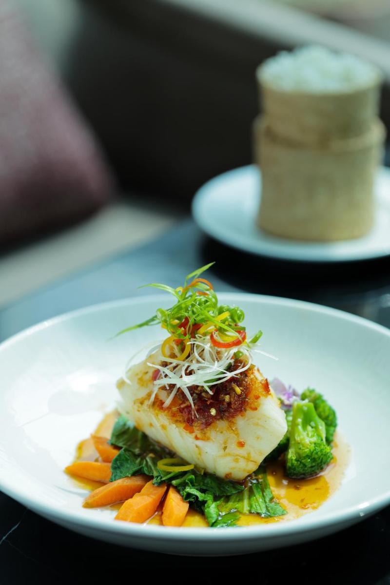 a plate of food with fish and vegetables on a table at The Leela Palace New Delhi in New Delhi a plate of food with fish and vegetables on a table at The Leela Palace New Delhi in New Delhi