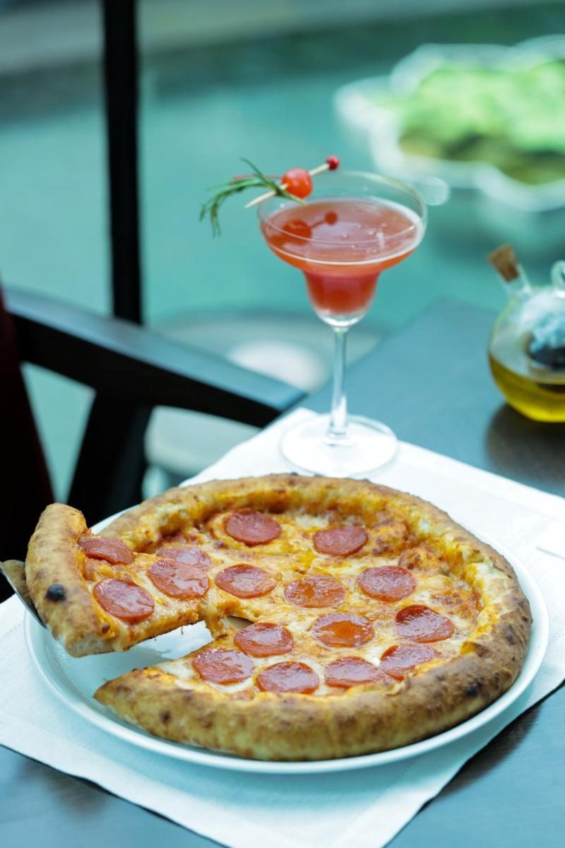 a pepperoni pizza on a plate next to a drink at The Leela Palace New Delhi in New Delhi a pepperoni pizza on a plate next to a drink at The Leela Palace New Delhi in New Delhi