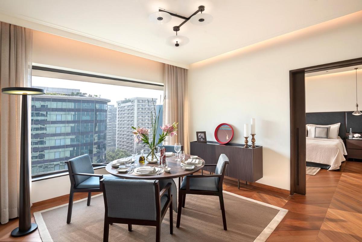 a dining room with a table and chairs and a bedroom at The Oberoi Mumbai in Mumbai