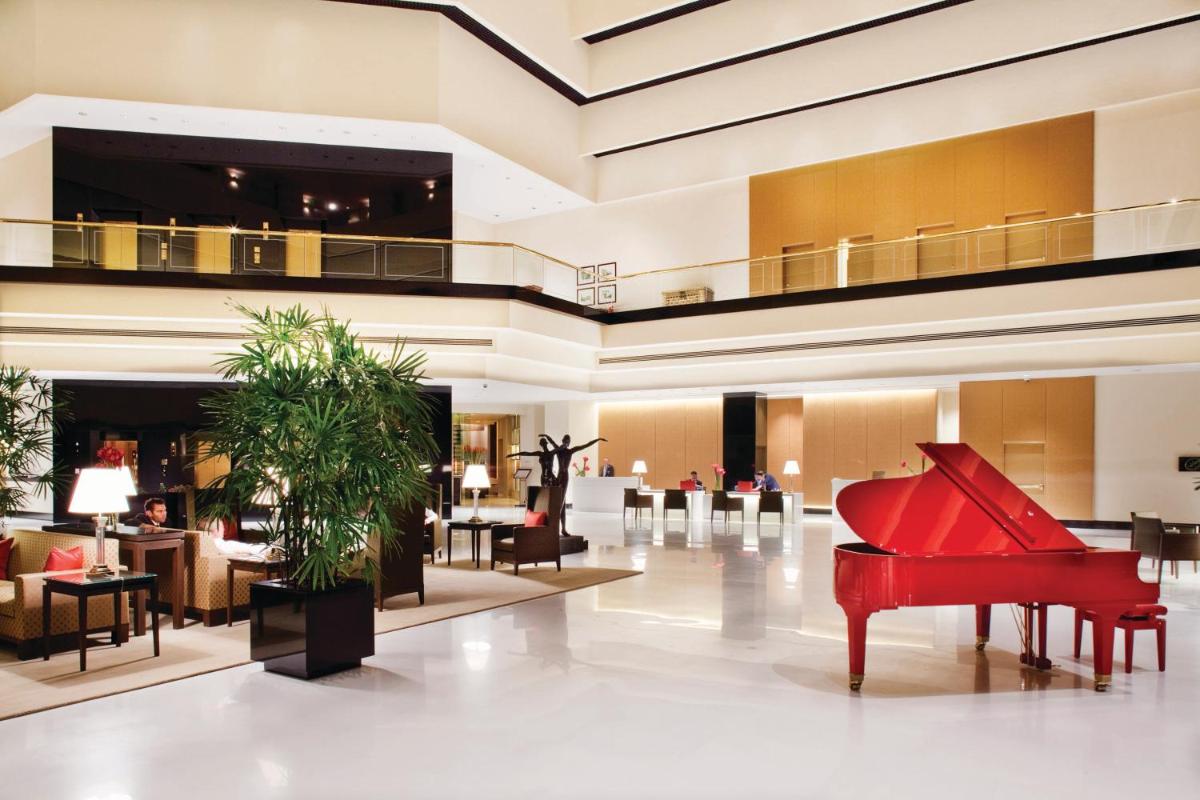 a large lobby with a red piano in the middle at The Oberoi Mumbai in Mumbai