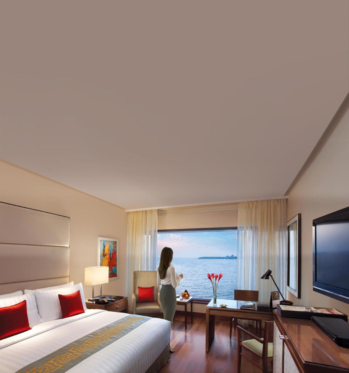 a woman standing in a hotel room looking out the window at The Oberoi Mumbai in Mumbai