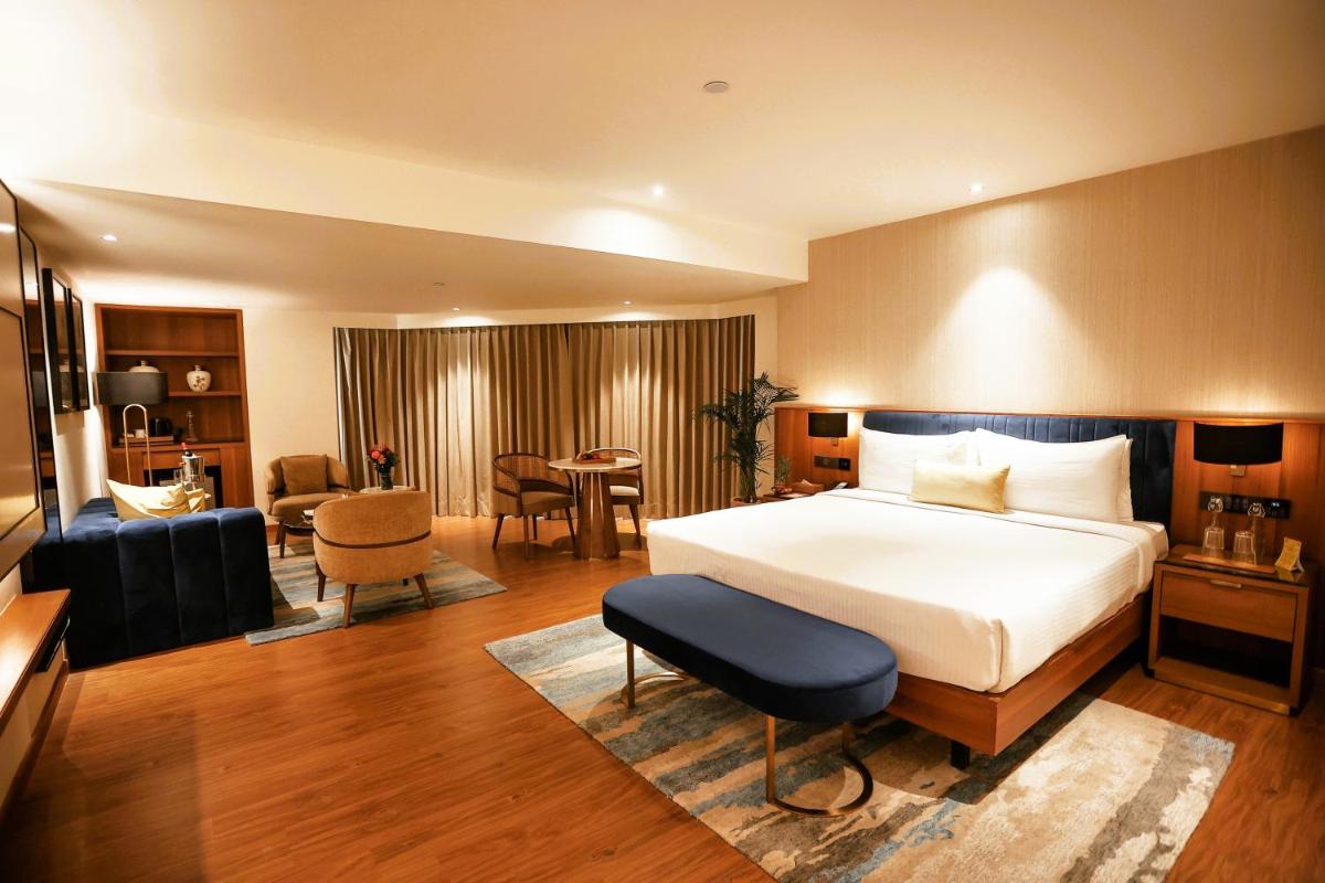a hotel room with a bed and a living room at Golden Tulip Jaipur in Jaipur