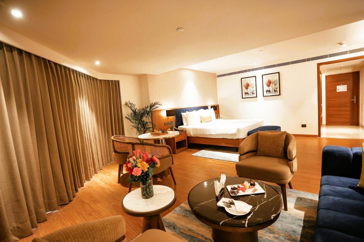 a hotel room with a bed and a living room at Golden Tulip Jaipur in Jaipur