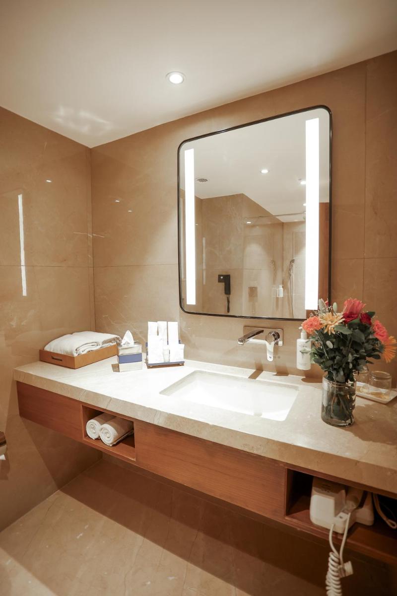 a bathroom with a sink and a large mirror at Golden Tulip Jaipur in Jaipur