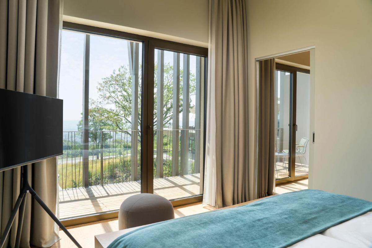 ein Schlafzimmer mit einem Bett und einem großen Fenster in der Unterkunft WALDWEIT Rheingau Hotel und Retreat in Kiedrich