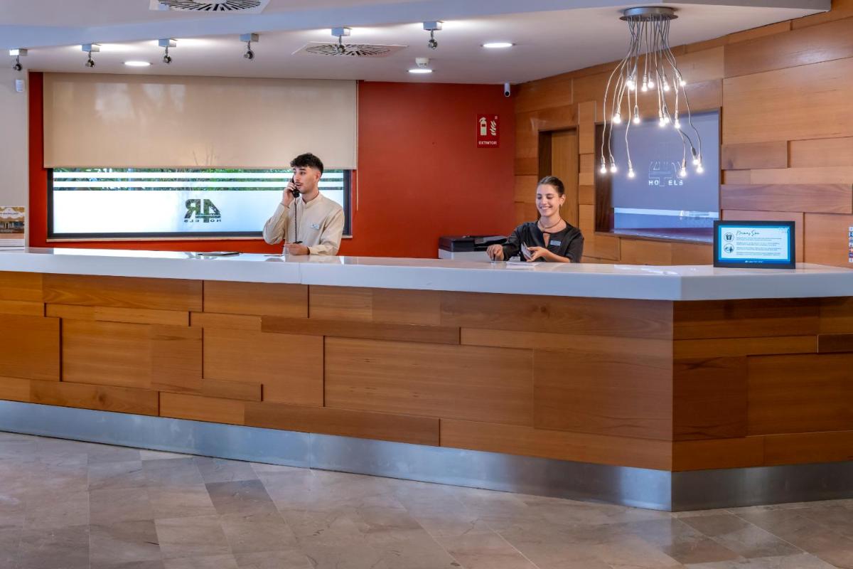 Dos hombres hablando por teléfonos celulares en un mostrador de recepción en 4R Salou Park Resort II, en Salou 37 fotos más