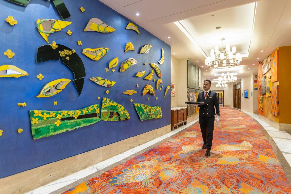 a man in a suit is standing in a hallway at The Leela Ambience Gurugram Hotel & Residences - The Luxury Urban Sanctuary in Gurgaon