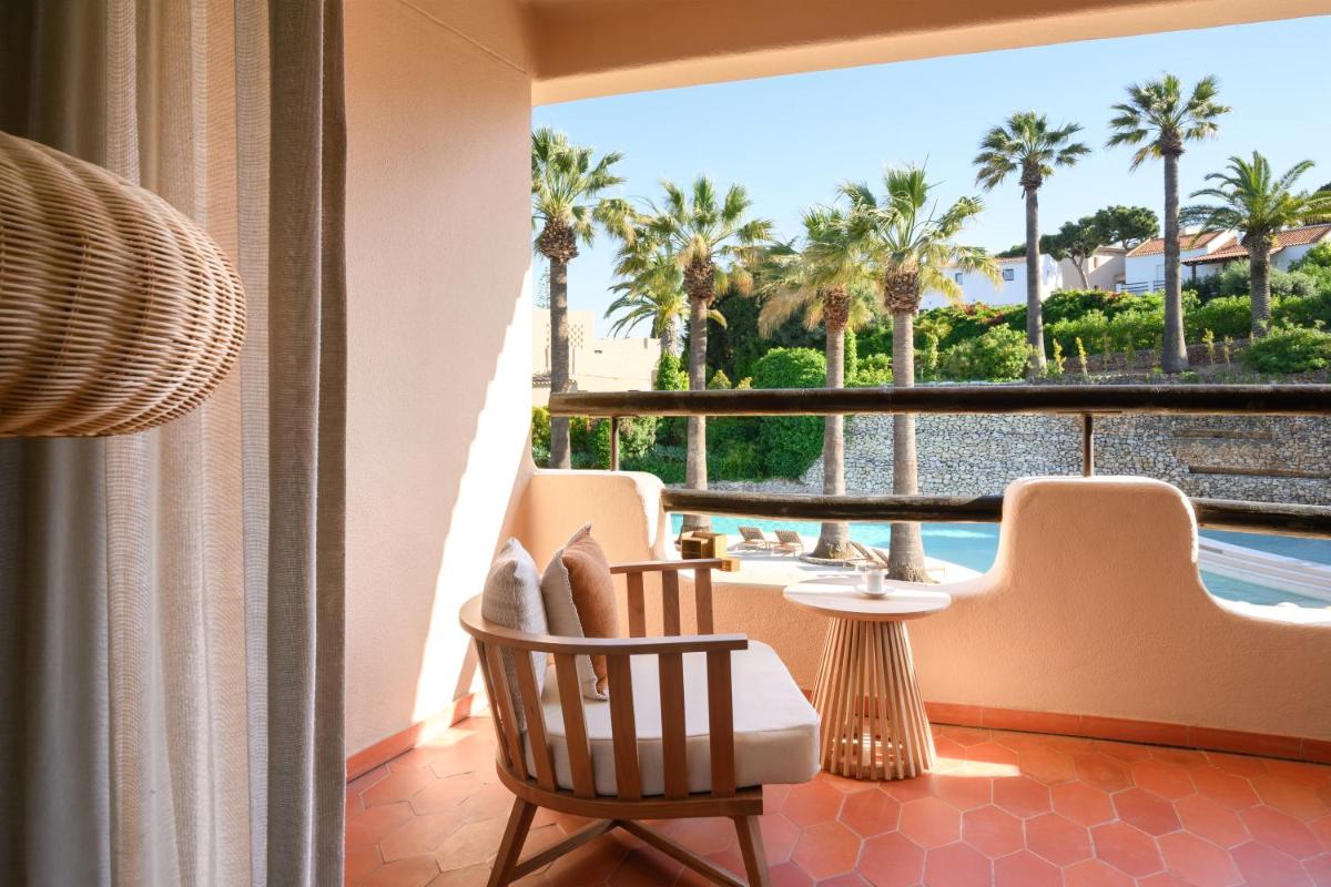uma varanda com vista para uma piscina e palmeiras em Vilalara Grand Hotel Algarve em Armação de Pêra