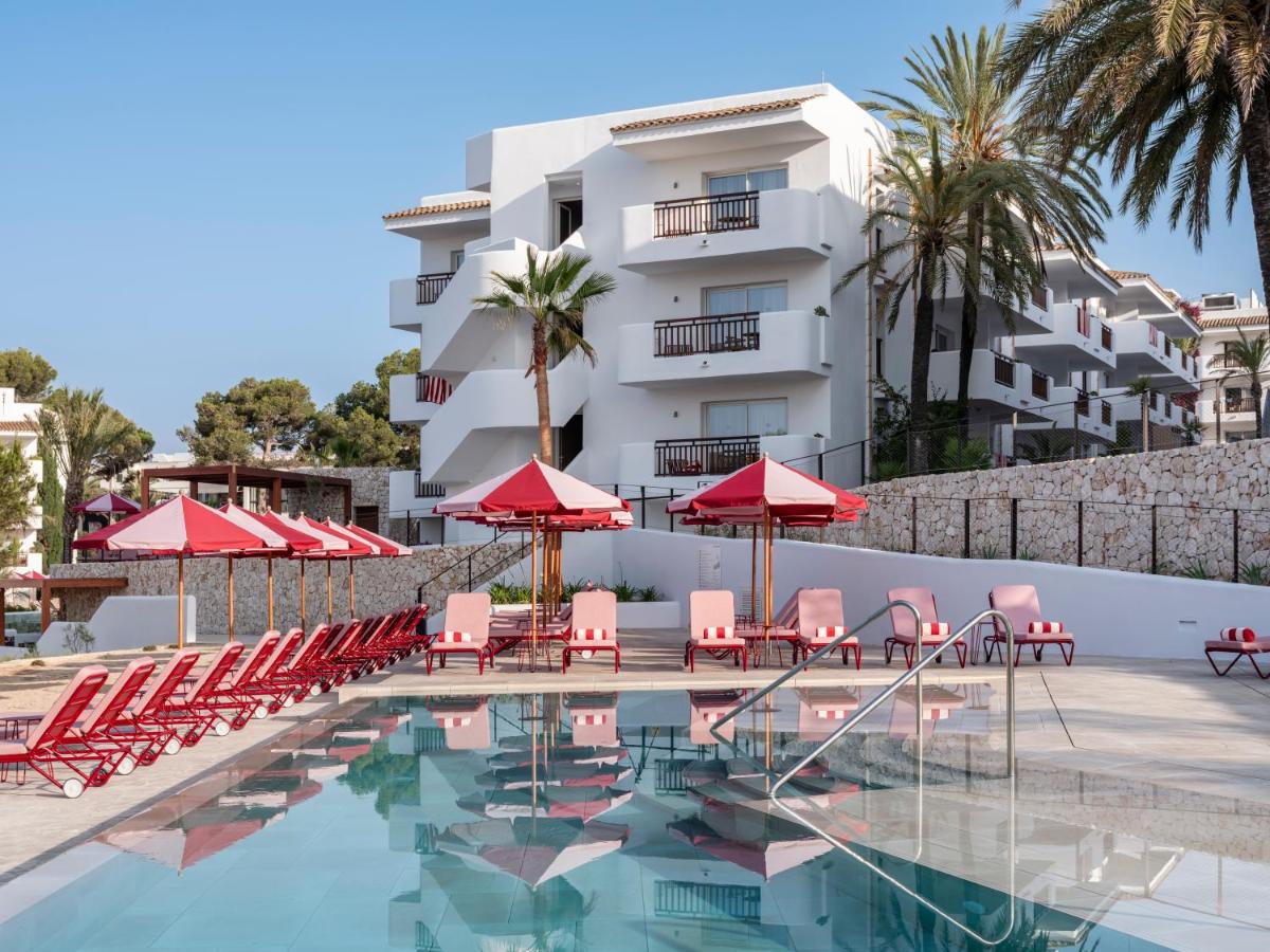 una piscina de hotel con sillas y sombrillas rojas en Inturotel Esmeralda Park, en Cala d´Or