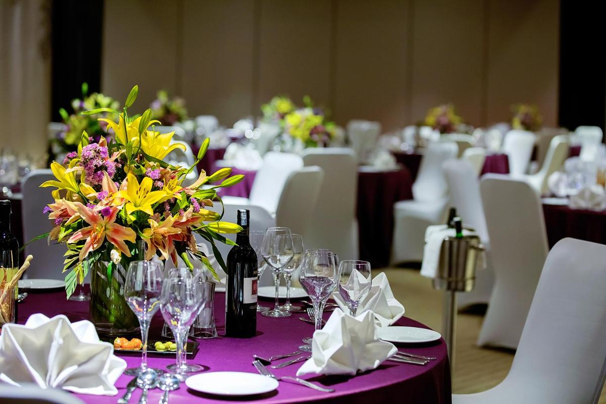 a table with a purple table cloth with flowers and wine bottles at Grand Mercure Mysore - An Accor Brand in Mysore