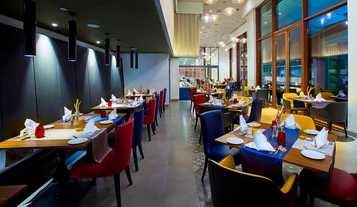 a dining room with tables and chairs in a restaurant at Grand Mercure Mysore - An Accor Brand in Mysore