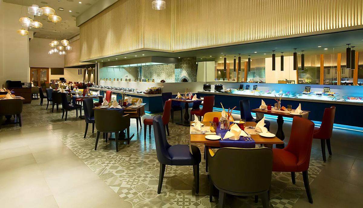 a dining room with tables and chairs in a restaurant at Grand Mercure Mysore - An Accor Brand in Mysore