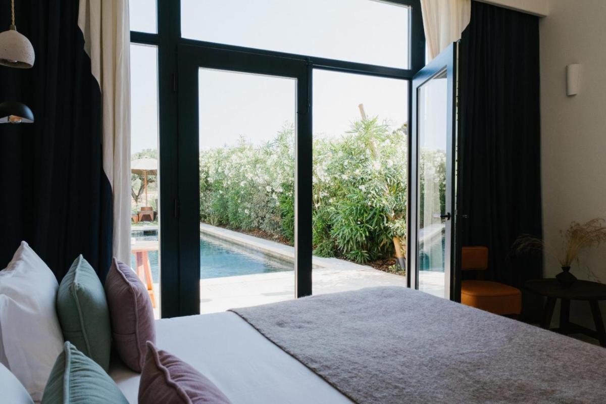 Un dormitorio con una cama y una ventana grande. en CAP Menorca Relais & Chateaux, en Son Bou