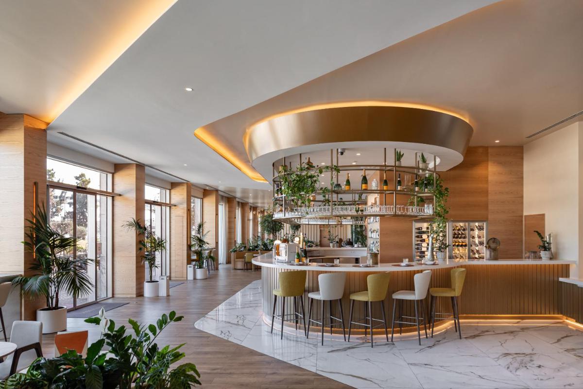 um átrio com um bar com bancos amarelos em Hyatt Regency Lisbon em Lisboa
