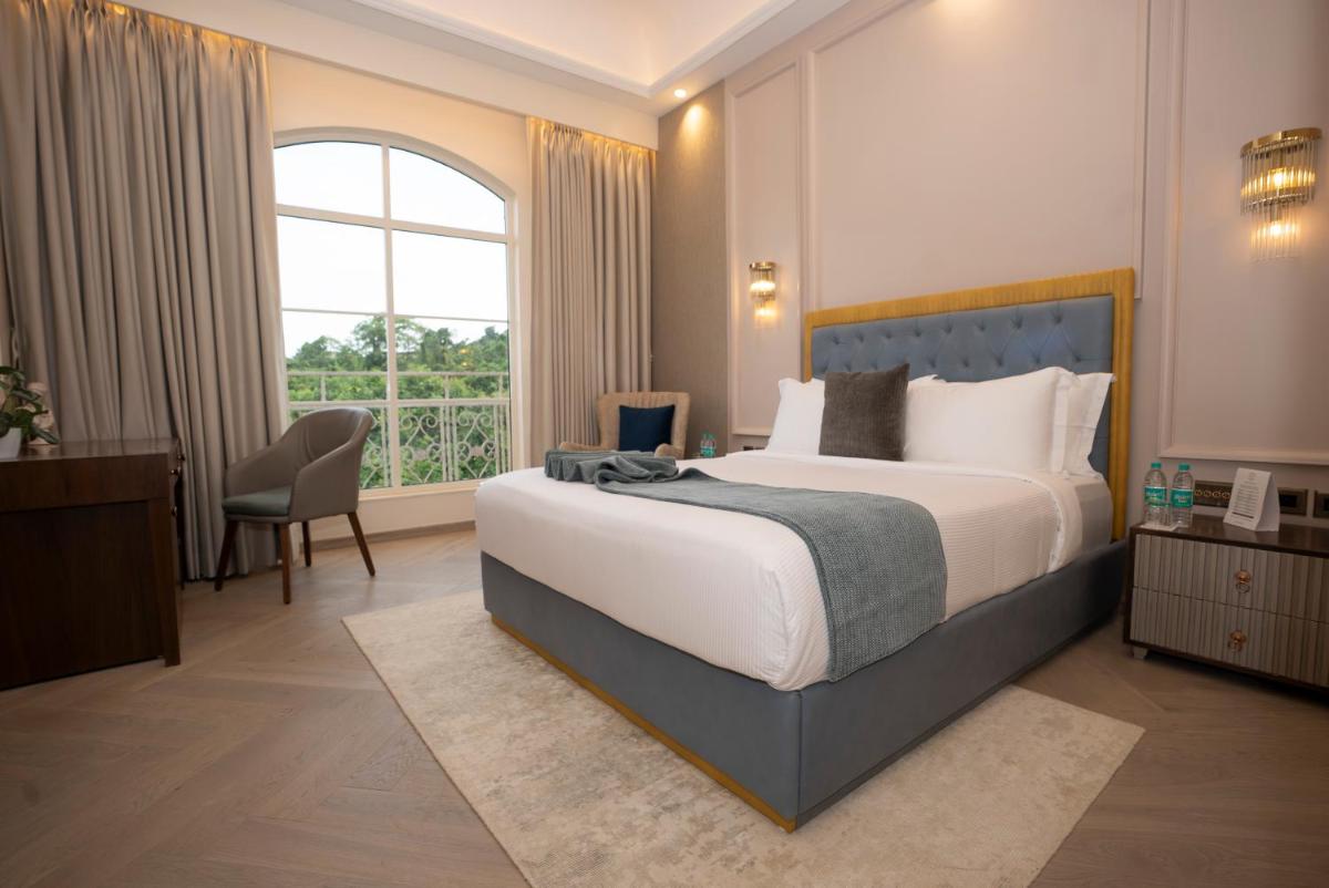 a bedroom with a large bed and a large window at Miros - Formerly Imperial Goa in Old Goa