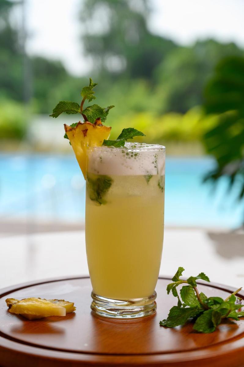 a drink with a piece of fruit in a glass at Miros - Formerly Imperial Goa in Old Goa