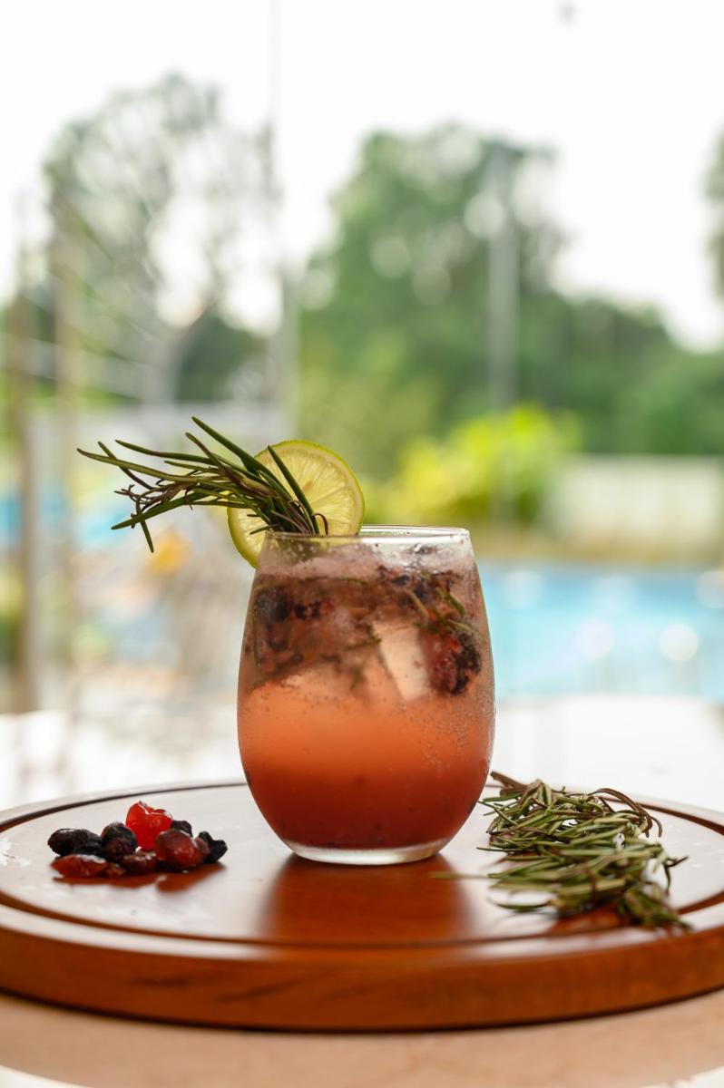 a drink sitting on a wooden plate with a drink at Miros - Formerly Imperial Goa in Old Goa