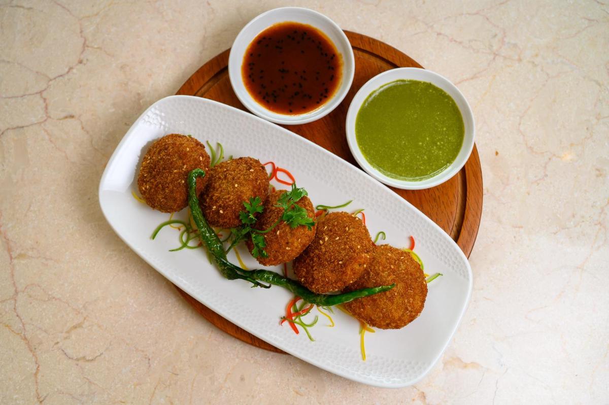 a plate of food with meatballs and a bowl of dipping sauce at Miros - Formerly Imperial Goa in Old Goa