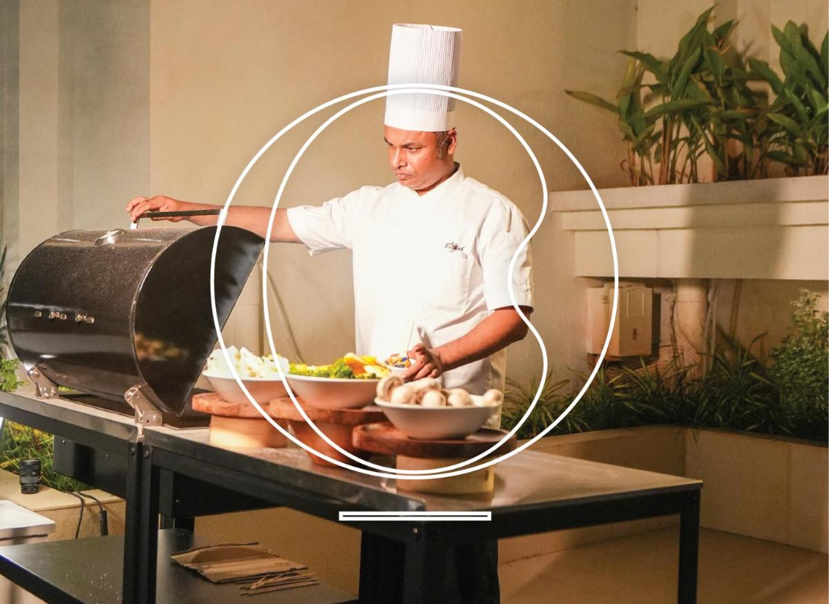 a chef standing in a kitchen preparing food at Miros - Formerly Imperial Goa in Old Goa