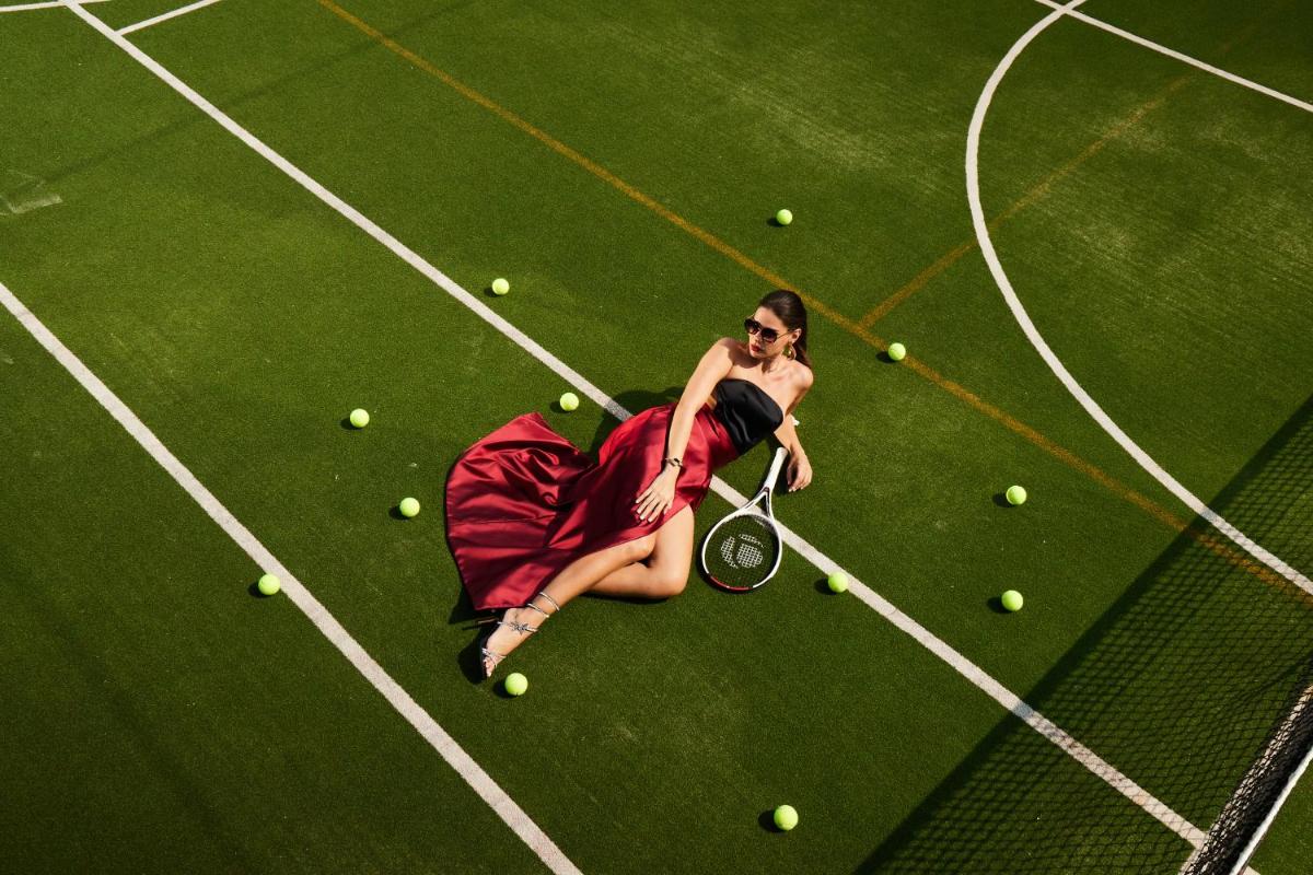 a woman sitting on a tennis court with a racket at Miros - Formerly Imperial Goa in Old Goa