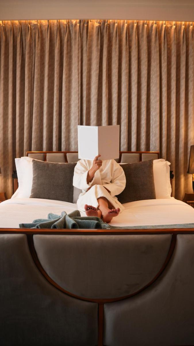 a woman laying on a bed reading a book at Miros - Formerly Imperial Goa in Old Goa
