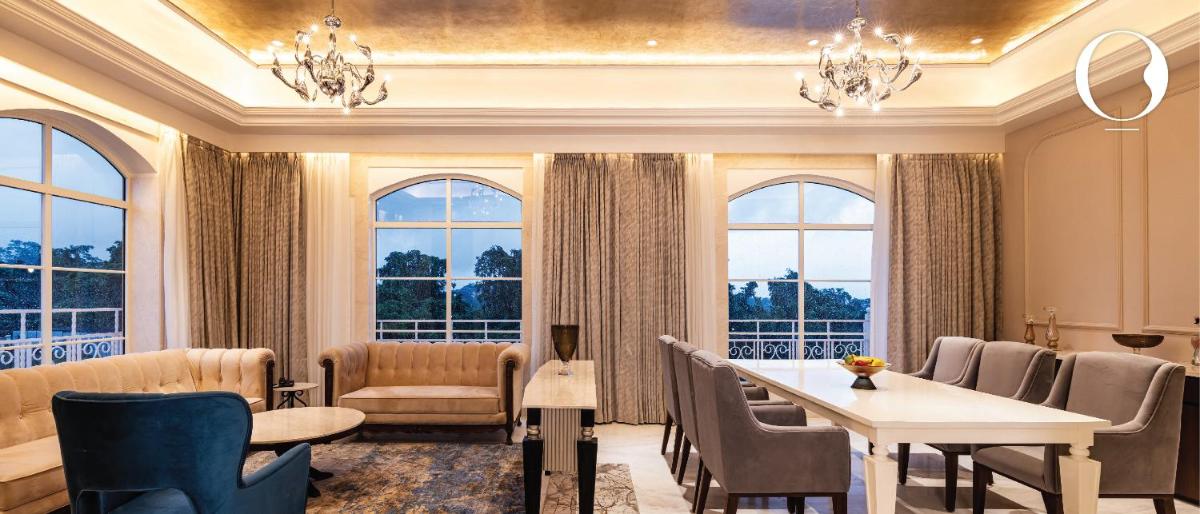 a living room with a table and chairs and windows at Miros - Formerly Imperial Goa in Old Goa