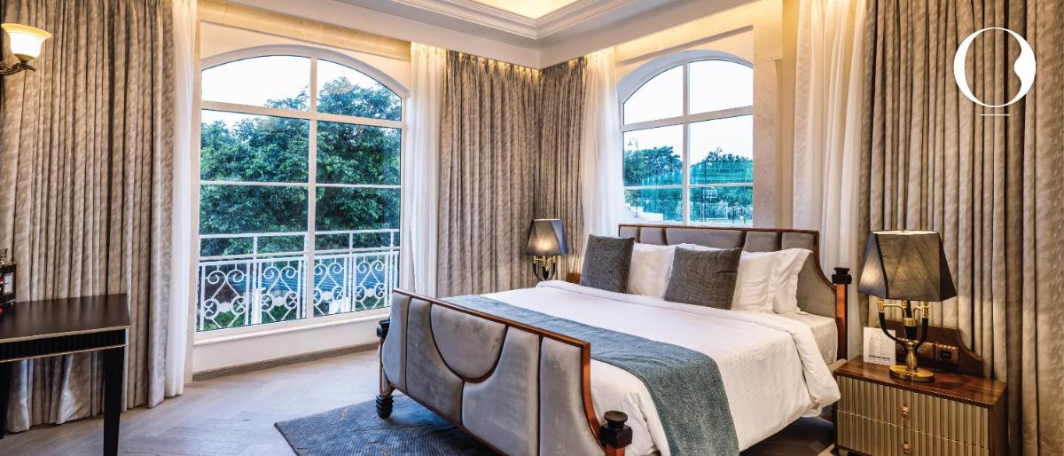 a bedroom with a bed and two large windows at Miros - Formerly Imperial Goa in Old Goa