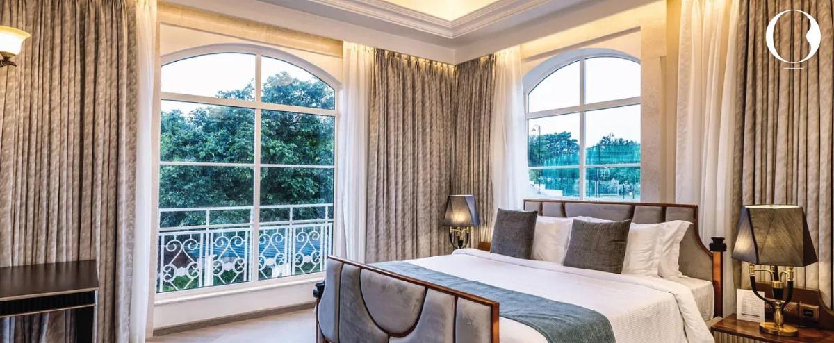 a bedroom with a bed and a large window at Miros - Formerly Imperial Goa in Old Goa