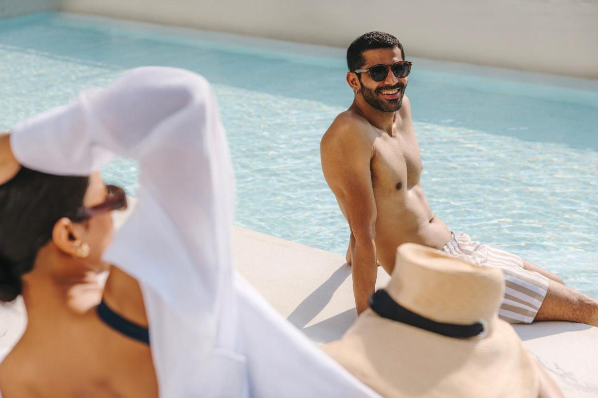 two men sitting on the edge of a swimming pool at Fairmont Mumbai in Mumbai