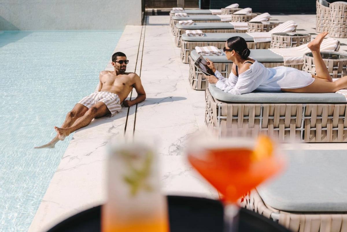 a man and a woman sitting next to a swimming pool at Fairmont Mumbai in Mumbai