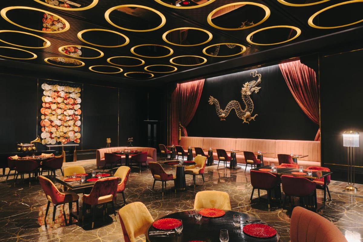 a restaurant with tables and chairs and a dragon on the ceiling at Fairmont Mumbai in Mumbai