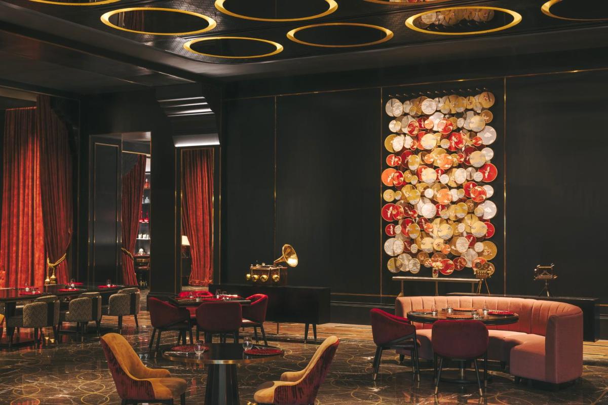 a dining room with tables and chairs and a wall of plates at Fairmont Mumbai in Mumbai